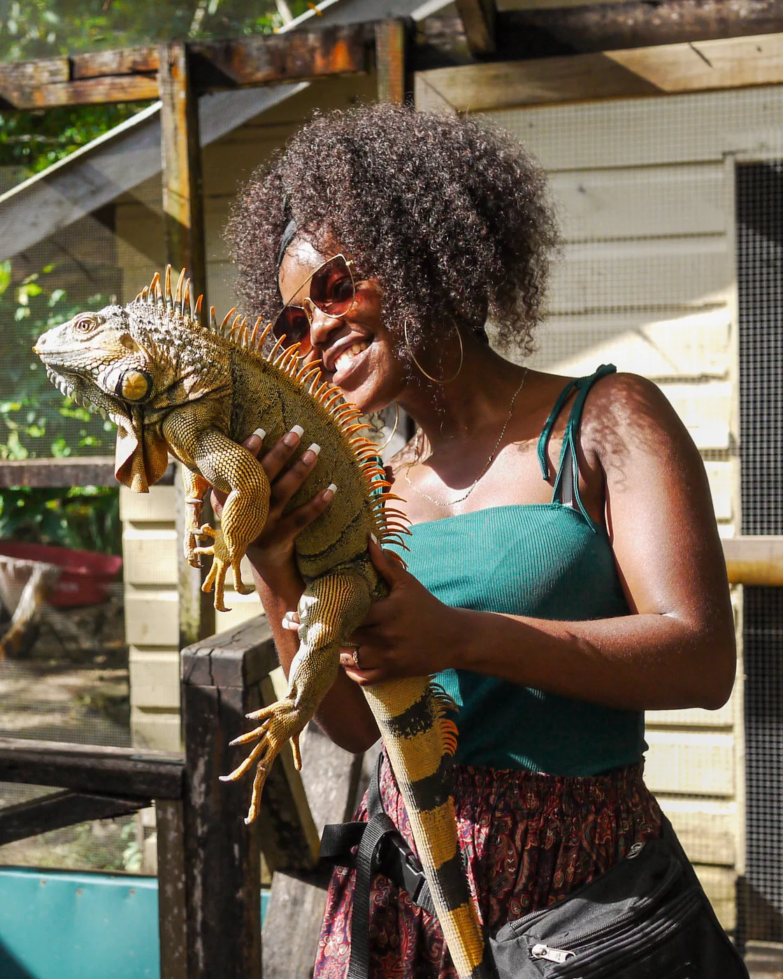 Documentary travel photography — woman smiling and holding a large iguana outdoors