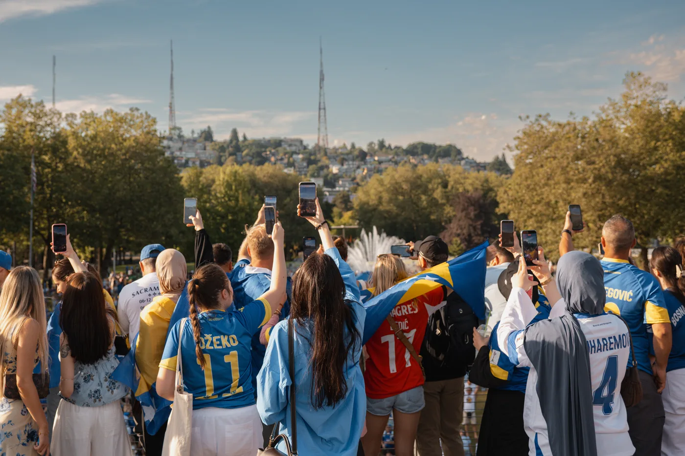 Documentary event photography — crowd raising phones to film a World Cup celebration in the park